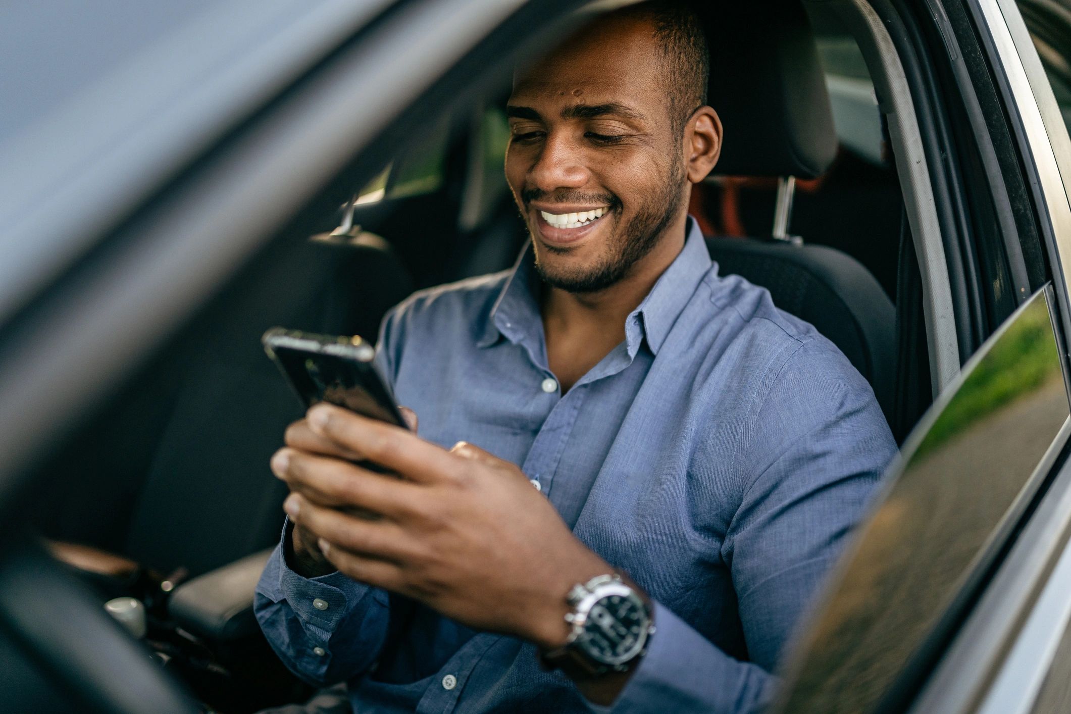 Driver using a smartphone in a parked car to request an auto insurance quote